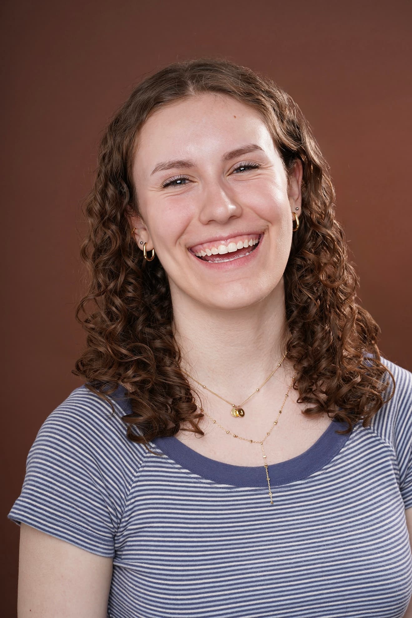 Maya Cassell smiling headshot on a warm studio backdrop