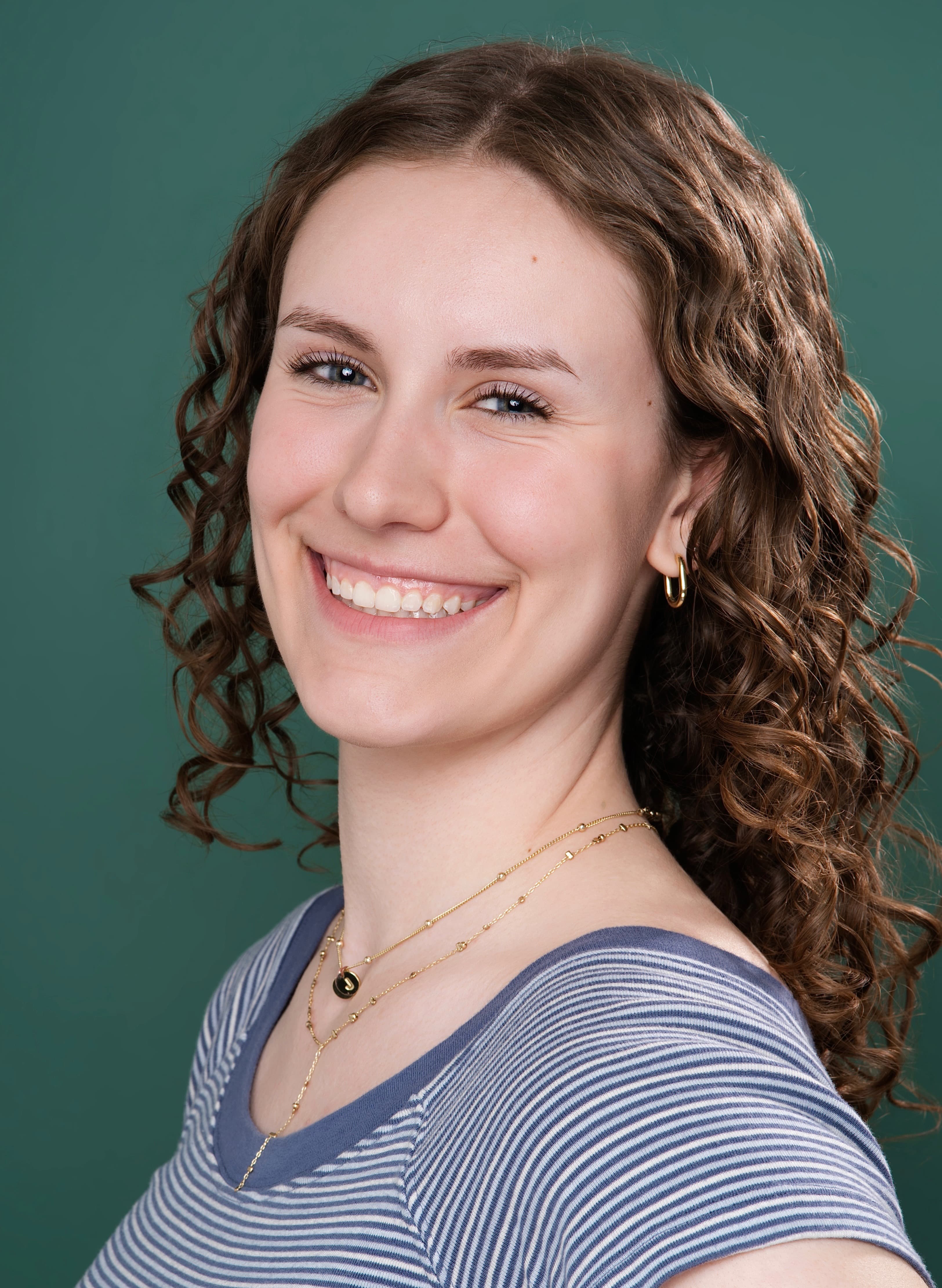 Maya Cassell smiling headshot on a teal backdrop